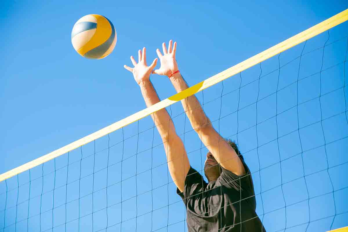 Photo of man hitting volleyball over net